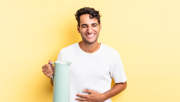 Hispanic handsome man laughing out loud at some hilarious joke. coffee thermos concept