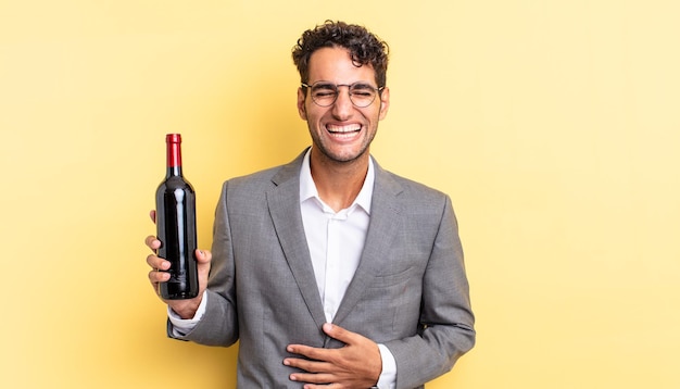 Hispanic handsome man laughing out loud at some hilarious joke. wine bottle concept