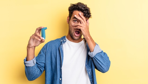 Hispanic handsome man looking shocked, scared or terrified, covering face with hand. asthma concept