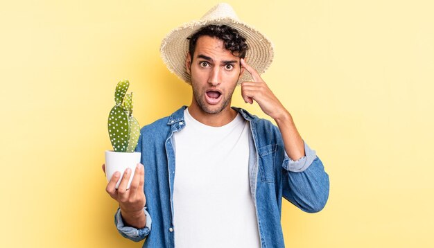 Hispanic handsome man looking surprised, realizing a new thought, idea or concept farmer and cactus concept