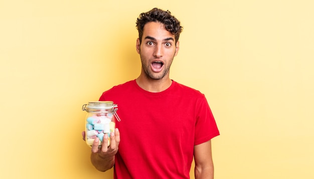 Hispanic handsome man looking very shocked or surprised. candies concept