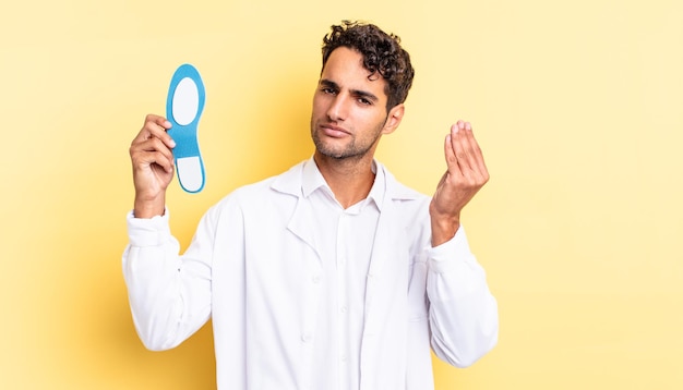 Hispanic handsome man making capice or money gesture, telling you to pay. chiropodist concept