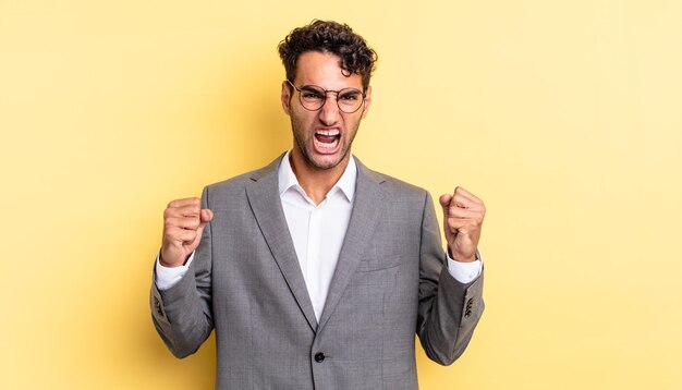 Hispanic handsome man shouting aggressively with an angry expression. business concept