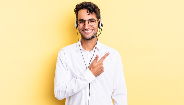 Hispanic handsome man smiling cheerfully, feeling happy and pointing to the side. telemarketer concept