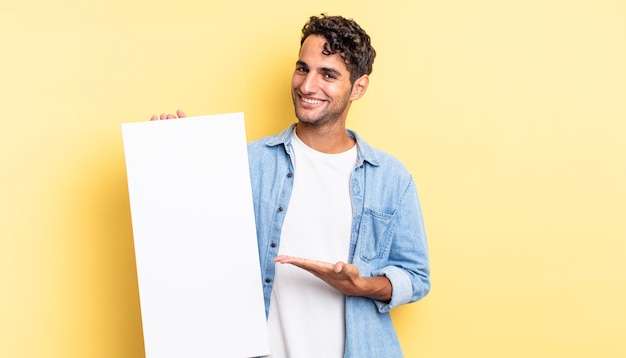 Hispanic handsome man smiling cheerfully, feeling happy and showing a concept. empty canvas concept