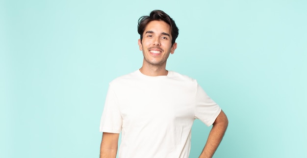 hispanic handsome man smiling happily with a hand on hip and confident, positive, proud and friendly attitude