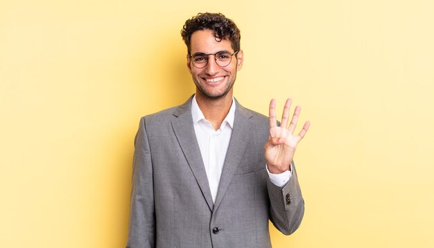 Hispanic handsome man smiling and looking friendly showing number four business concept