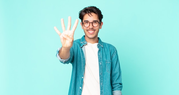 Hispanic handsome man smiling and looking friendly, showing number four or fourth with hand forward, counting down