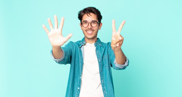 Hispanic handsome man smiling and looking friendly, showing number seven or seventh with hand forward, counting down
