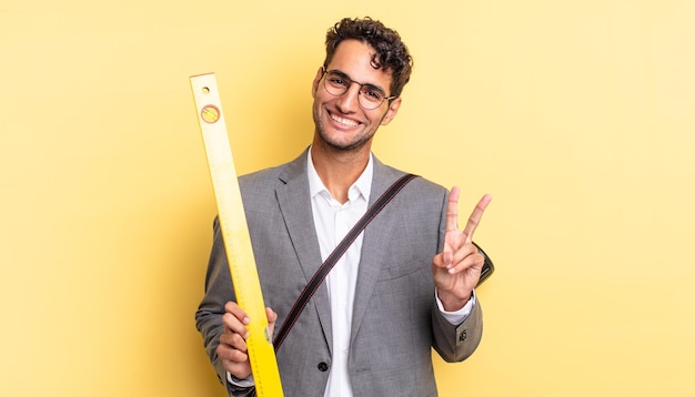 Hispanic handsome man smiling and looking happy gesturing victory or peace architect concept