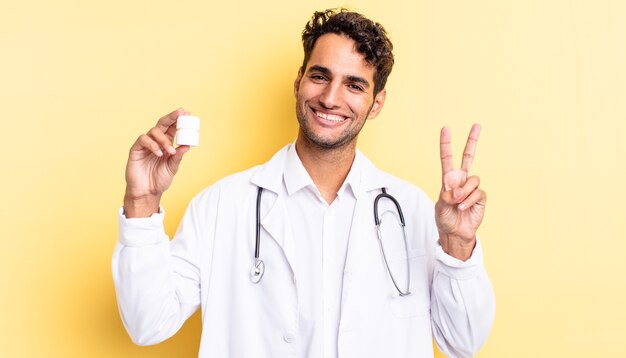 Ispanico bell'uomo che sorride e sembra felice, gesticolando vittoria o pace. concetto di pillole bottiglia medico