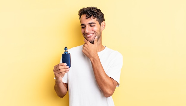 Hispanic handsome man smiling with a happy, confident expression with hand on chin. vaporizer concept