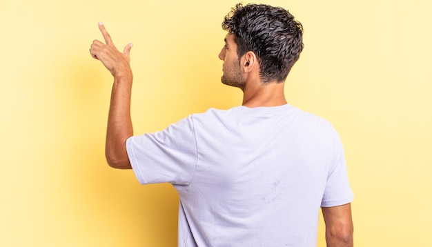 Hispanic handsome man standing and pointing to object on copy space