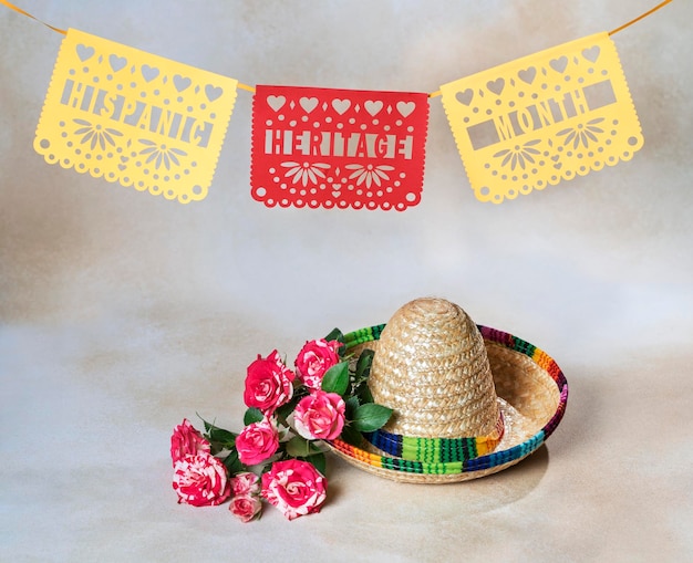 Фото Фон месяца латиноамериканского наследия с мексиканскими бумажными флагами, соломенной шляпой и цветами