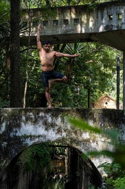 Photo hispanic and latin man meditating in the middle of a forest receiving sun rays brown skin mexico