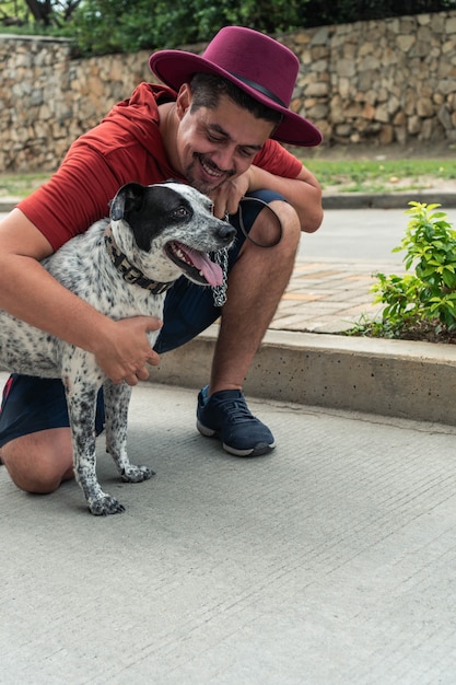 ヒスパニック系の男性が犬に微笑んで、腰をかがめた