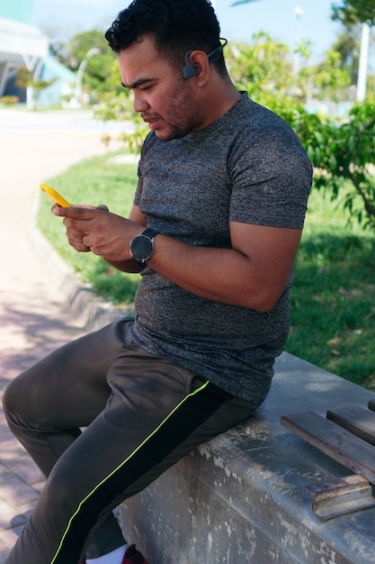Испаноязычный мужчина проверяет свой мобильный телефон во время тренировки на открытом воздухе
