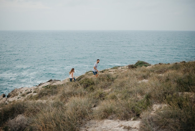 A Hispanic man and his Latina girlfriend are hiking near the sea in Spain