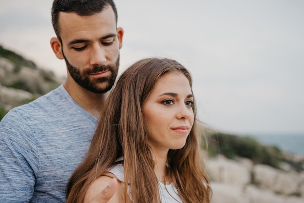 A Hispanic man is hugging a Latina girl on the rocky sea coast in Spain