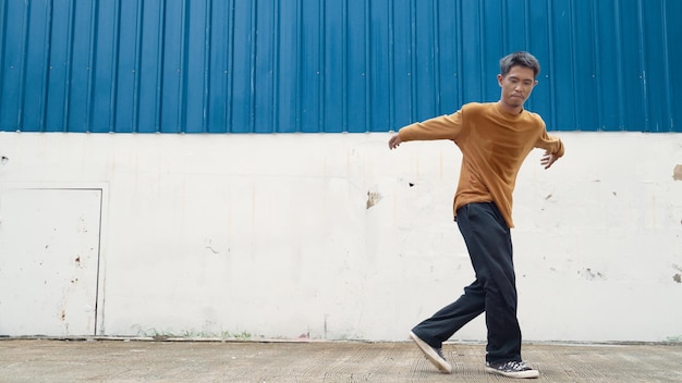 Hispanic man stretch arms and dance street dancing in front of wall Endeavor