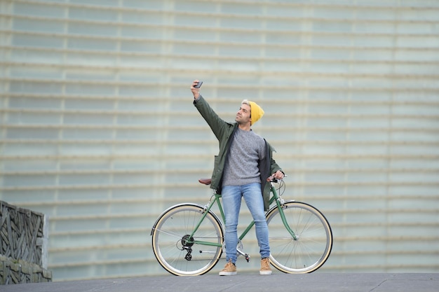 Hispanic man taking a selfie while holding a classic bicycle