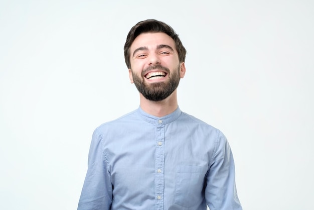 Hispanic man wearing blue shirt laughing or grinning having cheerful look