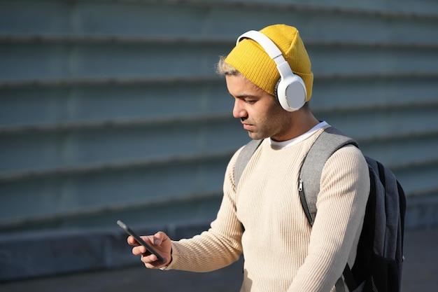 Photo hispanic man wearing headphones choosing music on his phone