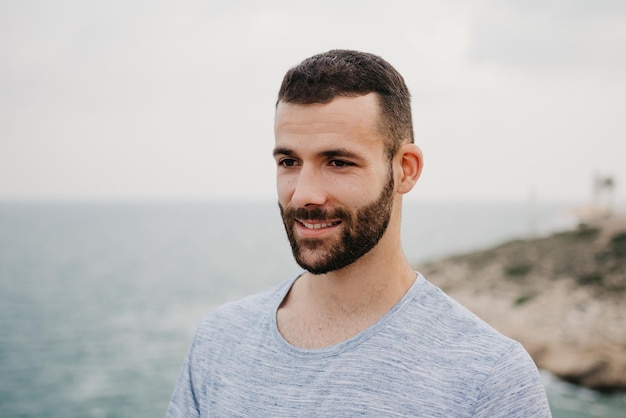 A Hispanic man with a beard near the sea in a highland park in Spain