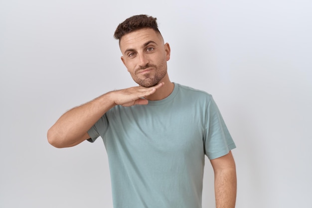 Hispanic man with beard standing over white background cutting throat with hand as knife threaten aggression with furious violence