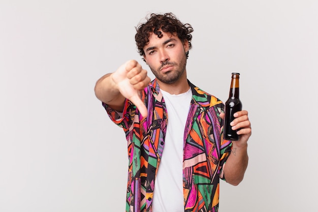 Hispanic man with beer feeling cross, angry, annoyed, disappointed or displeased, showing thumbs down with a serious look