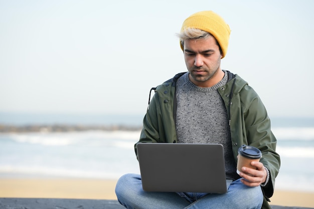 Photo hispanic man working on his laptop outdoors