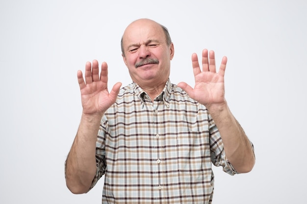 Hispanic mature man showing refusal gesture It is not for me leave me in piece