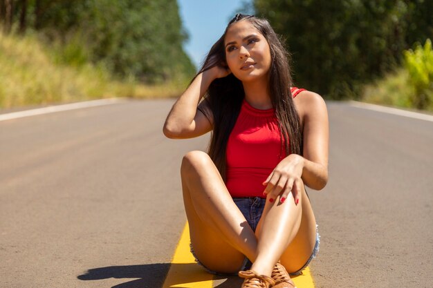 Hispanic meisje in het midden van de snelweg, de natuur op de achtergrond.