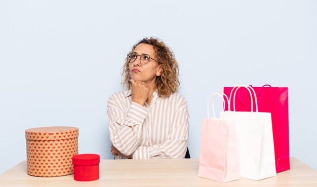 Hispanic middelbare leeftijd vrouw denken, twijfelachtig en verward voelen, met verschillende opties, zich afvragend welke beslissing ze moet nemen