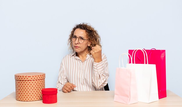 Hispanic middle age woman feeling angry, annoyed, rebellious and aggressive, flipping the middle finger, fighting back