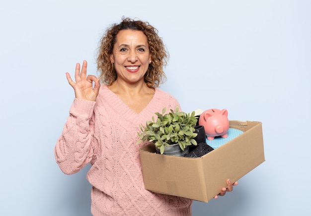 Hispanic middle age woman feeling happy, relaxed and satisfied, showing approval with okay gesture, smiling