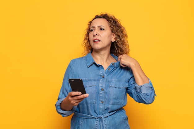 Hispanic middle age woman feeling stressed, anxious, tired and frustrated, pulling shirt neck, looking frustrated with problem