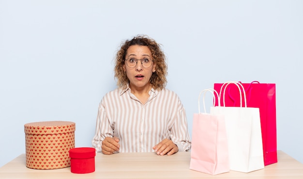 Hispanic middle age woman looking very shocked or surprised, staring with open mouth saying wow