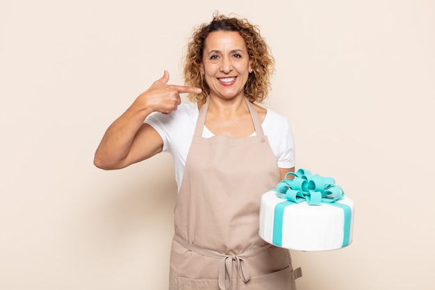 Hispanic middle age woman smiling confidently pointing to own broad smile, positive, relaxed, satisfied attitude