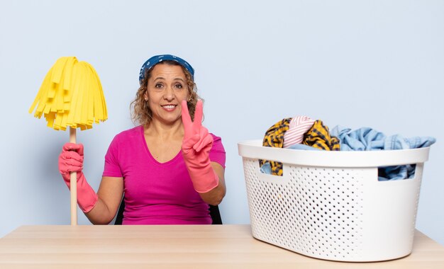 Hispanic middle age woman smiling and looking friendly, showing number two or second with hand forward, counting down