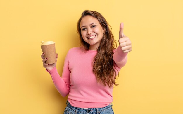 Hispanic mooie vrouw voelt zich trots, positief glimlachend met duimen omhoog. afhaal koffie concept