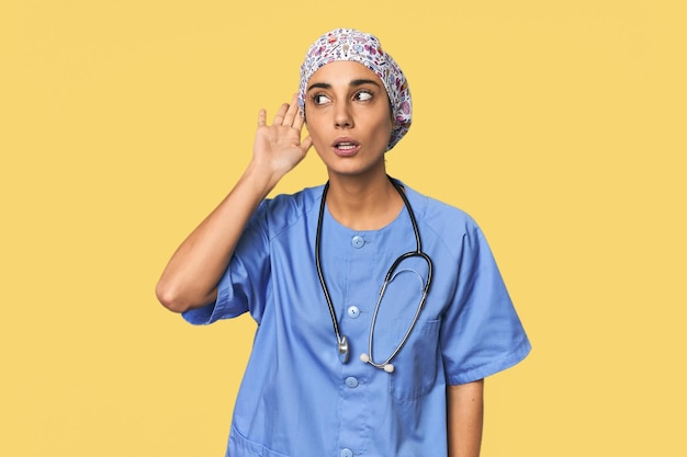 Hispanic nurse in uniform with stethoscope trying to listening a gossip