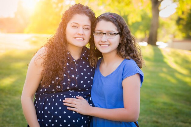 Photo hispanic pregnant mother with young daughter outdoors