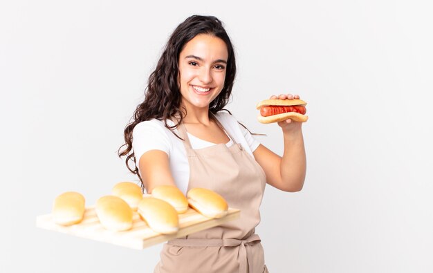 Испаноязычное довольно шеф-повар женщина держит тройской хлеб булочки