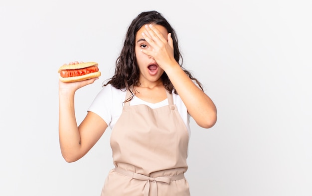 ホットドッグを保持しているヒスパニック系のかわいいシェフの女性