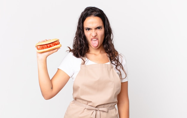 Hispanic pretty chef woman holding a hot dog