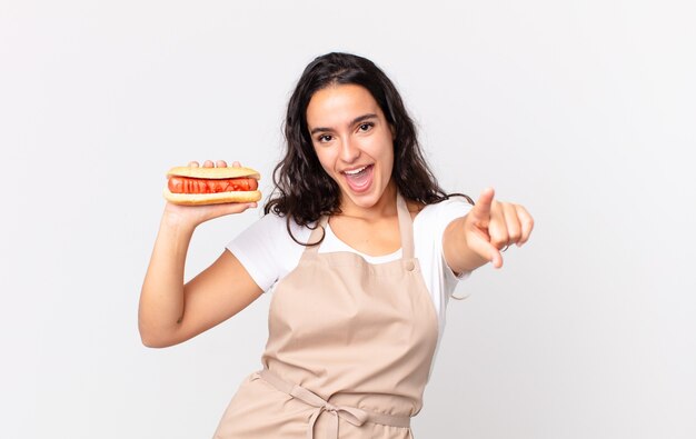 Hispanic pretty chef woman holding a hot dog