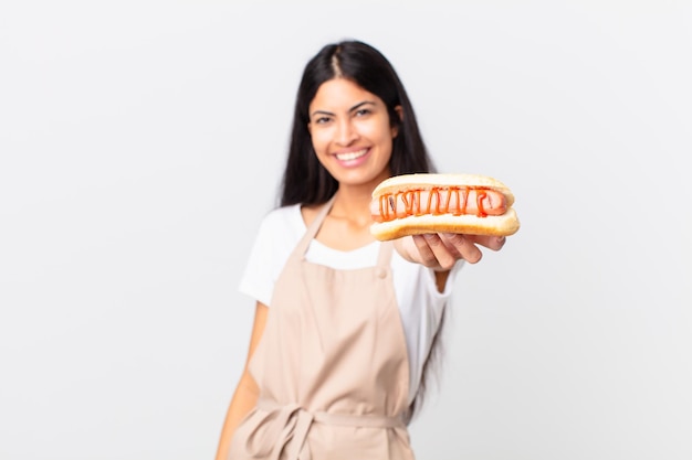 Hispanic pretty chef woman holding a hot dog