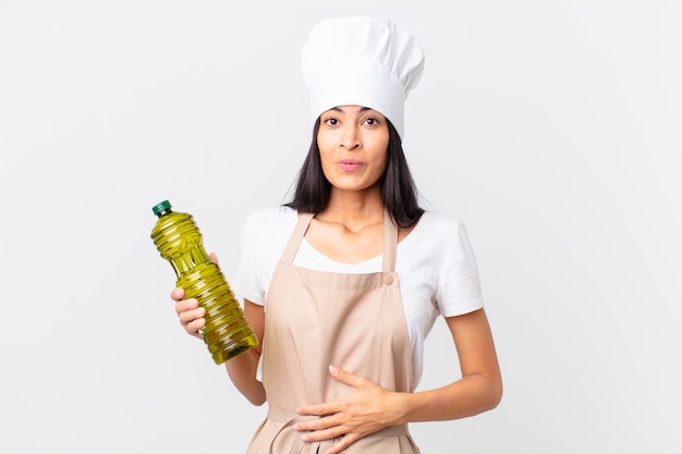 Hispanic pretty chef woman holding an olive oil bottle.