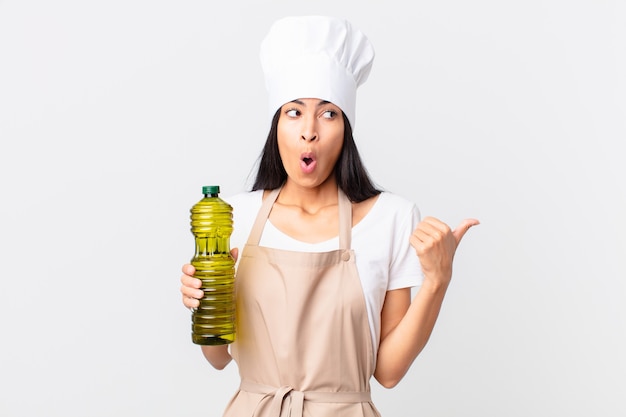 Hispanic pretty chef woman holding an olive oil bottle.